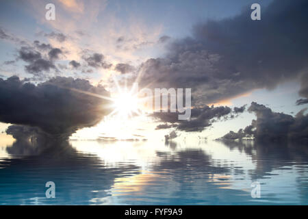 Dunkle Sturm mit Wasserreflexion. Ein Himmel von Wolken spiegeln sich in einem ruhigen Meer mit sunburst Stockfoto