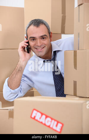 ein 40-45 Jahre alt-Mitarbeiter ruft jemand in einem Raum voller Kartons Stockfoto