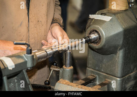 Eine Nahaufnahme von einem Drechsler bei der Arbeit mit einem Hand-Schneidwerkzeug auf einer hölzernen Spindel montiert auf einer Drehbank Stockfoto