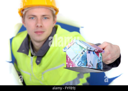 Ein Handwerker präsentieren ein Miniaturhaus machte der Euro-Scheine. Stockfoto