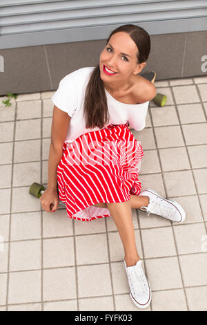 Hipster-Dame sitzt auf longboard Stockfoto