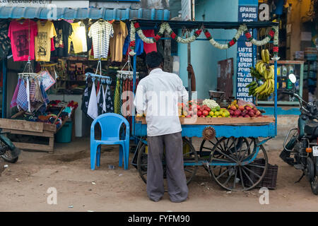 Indischer Mann mit Obst an einem mobilen Stand vor einem Bekleidungsgeschäft entlang der Chennai Road, Villupuram, Tamil Nadu, Indien Stockfoto