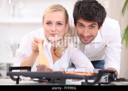 Paar, Kochen, Steak und Gambas auf einer Tischplatte Kochplatte Stockfoto