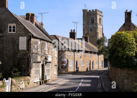 Blick entlang der Hauptstraße in Abbotsbury mit der Kirche des Heiligen Nikolaus im Hintergrund Stockfoto