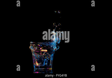 Hellen Cocktail im Glas und spritzt Wasser auf dunklem Hintergrund Stockfoto