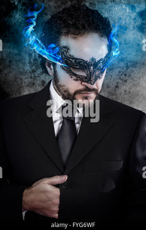 Konzept-Geschäft, Mann mit feurigen Augen und venezianische Maske trug schwarzes Kleid Stockfoto