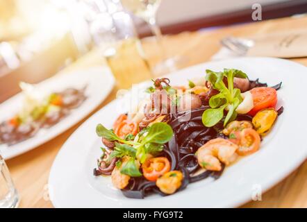 Italienische Küche servieren. Schwarze Nudeln mit Meeresfrüchten. Italienisches Essen. Stockfoto