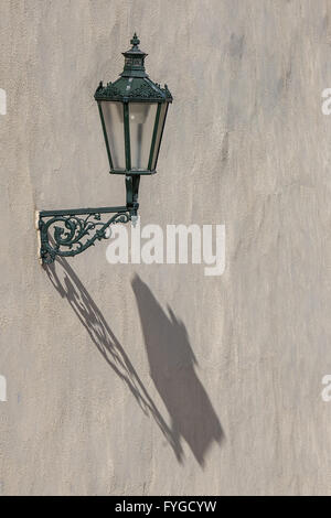 Oldtimer, historische Straßenlaterne mit langen schönen Schatten auf weiße Wand in Prag. Stockfoto