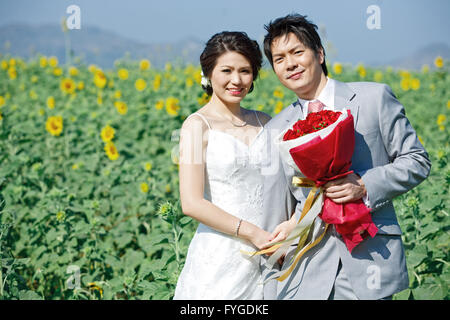 Porträt von Braut und Bräutigam am Sonnenblumenfeld Stockfoto