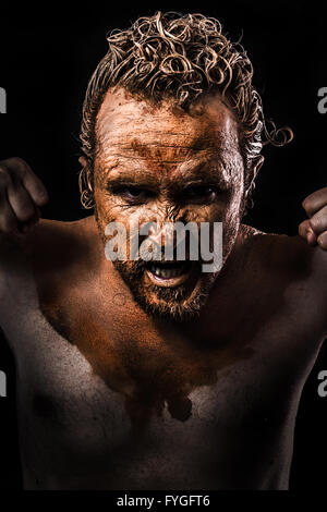 Anger Mann, junger Krieger in Schlamm bedeckt Stockfoto