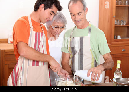 ein 20 Jahre alten Jungen und 65 Jahre alter Mann und eine Frau gemeinsam Kuchen machen Stockfoto