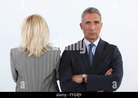 gut aussehend Geschäftsmann Kreuz bewaffnet und weibliche Businesspartner mit Rücken zur Kamera Stockfoto