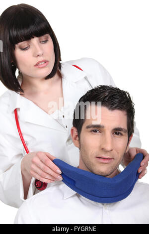 Brünette Krankenschwester männlichen Patienten Hals Halsband anziehen Stockfoto