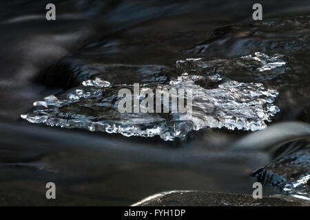 lange Exposition Bild des fließenden Wasser kaskadenförmig über Eis bedeckt Felsbrocken in einem stream Stockfoto