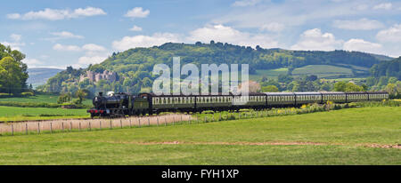 West Somerset Eisenbahn Dampf Zug 3850 vorbei Dunster Schloß mit den Hügeln von Exmoor in der Ferne im Jahr 2015. Stockfoto