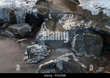 lange Exposition Bild des fließenden Wasser kaskadenförmig über Eis bedeckt Felsbrocken in einem stream Stockfoto