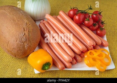 Rohe Frankfurter Würstchen und Brot auf weißen Teller Stockfoto