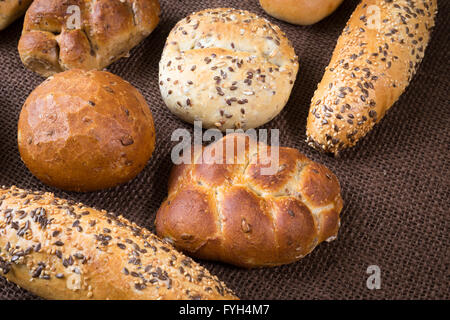 Verschiedene Arten von Vollkorn Brot und Brötchen auf braunem Hintergrund Stockfoto