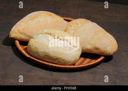 Verschiedene Arten von Brötchen, Kuchen, Brötchen, in einem Korb auf einer rustikalen hölzernen Oberfläche Stockfoto