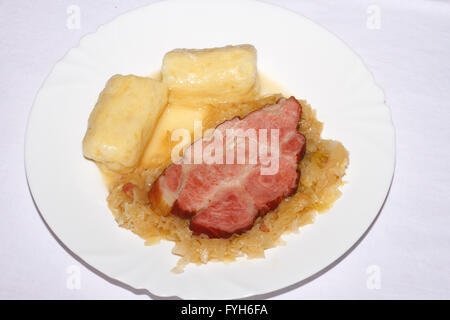 Ein Stück Schweinebraten mit Kartoffelknödel und Sauerkraut auf einem Teller Stockfoto