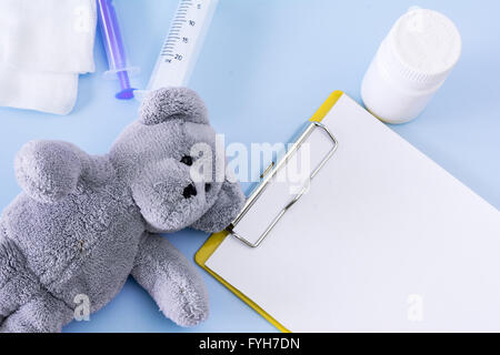 Medizinische Darstellung mit Teddybär, Injektion, Gaze, Flasche, Pillen, leeren Zwischenablage Blatt. Stockfoto