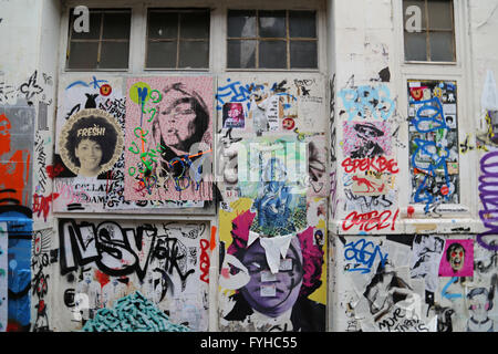 Graffiti und Street Art im Bereich trendige Hipster von Shoreditch in London, mit Plakaten und Farben oben an der Wand. Stockfoto