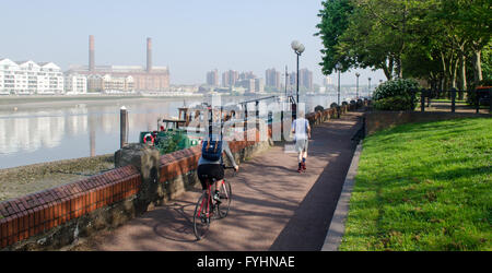 Nicht identifizierbare Radfahrer und Jogger auf einem Pfad an der Themse in Battersea, London. Stockfoto