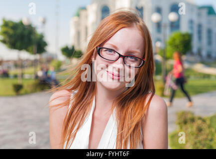 Schöne 20er Jahre Alter Rothaarige lächelnde Frau im Freien in Gläsern Stockfoto