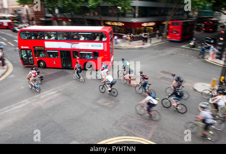 Eine Gruppe von Radfahrern Pendler auf den Weg von ein grünes Licht an einer belebten Straßenkreuzung im Zentrum von London. Stockfoto