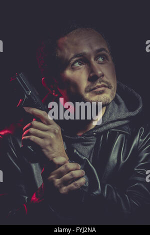 Mann mit einer Pistole und gekleidet in schwarzem Leder Stockfoto