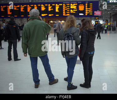 Familie in Glasgow Hauptbahnhof Bahnhof telefonieren suchen Ankünfte board Stockfoto