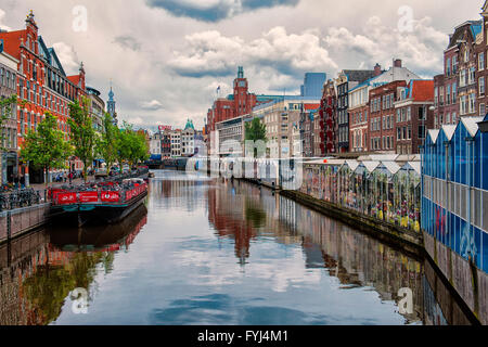 Amsterdam, Niederlande. Die schöne Singel-Kanal mit seinen Spiegelungen des Himmels und der Wolken. Rechts neben dem berühmten Blumenmarkt Stockfoto