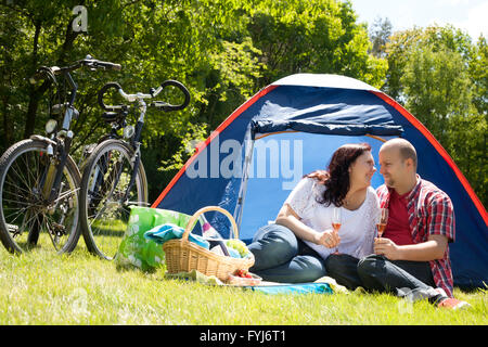 Glückliches Paar auf einem camping trinken prosecco Stockfoto