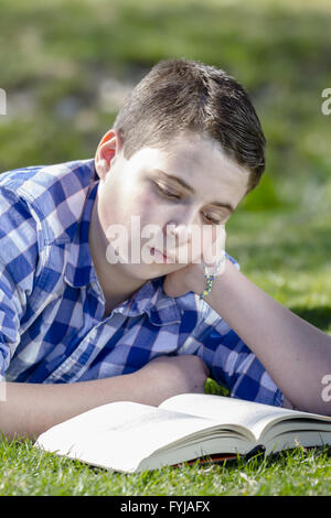 Kleiner Junge liest ein Buch im Wald mit geringer Tiefe Feld und Kopie Stockfoto