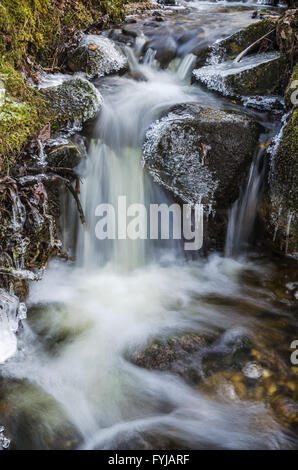 Kleiner Wasserfall mit Eiszapfen und Eis in der Nähe bis Frühling. Stockfoto