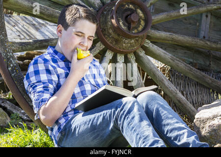 Relax.Young Junge liest ein Buch im Wald einen Apfel essen Stockfoto