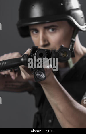 Schüsse, Paintball-Sport-Spieler tragen Schutzhelm mit dem Ziel Pistole, schwarze Rüstung und Maschinengewehr Stockfoto