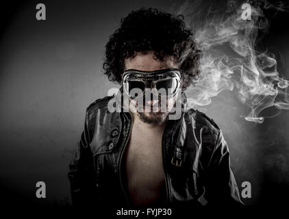 Heiß, Biker mit Sonnenbrillen-Ära gekleidet Lederjacke, riesige Rauch auf dunklem Hintergrund Stockfoto