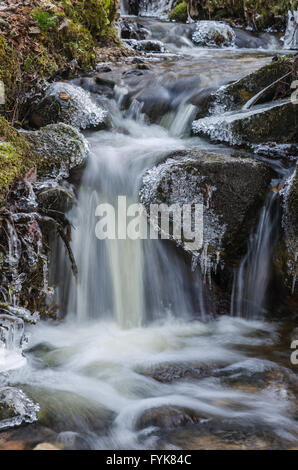 Kleiner Wasserfall mit Eiszapfen und Eis in der Nähe bis Frühling. Stockfoto