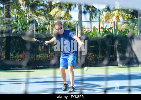 Pensionierter Mann in seinem 70er Jahre trifft einen Tennisball am Hof Stockfoto