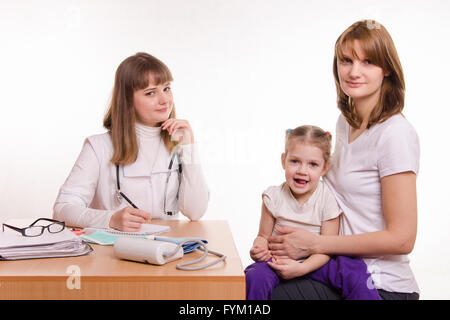 Kinderarzt, das Kind und seine Mutter sitzen am Schreibtisch im Büro Stockfoto