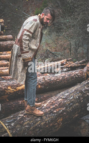 Junge Männer auf Baumstämmen im Wald. Leder und Jeans. Outdoor-Mode Stockfoto
