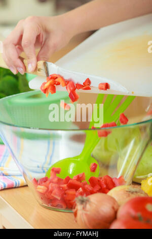 Gesunde Ernährung, vegetarische Speisen, Kochen, Diät und Menschen Konzept. Frau in der Küche zu Hause bereitet frischen Salat schneiden Gemüse Paprika in Schale zu werfen Stockfoto