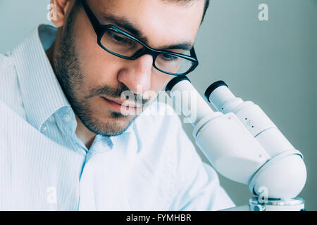 Jungen männlichen Arzt durch Mikroskop anzeigen Stockfoto