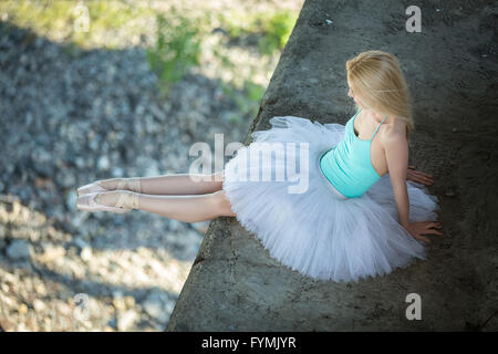 Ballerina, die sitzt auf dem Rand der Brücke Stockfoto