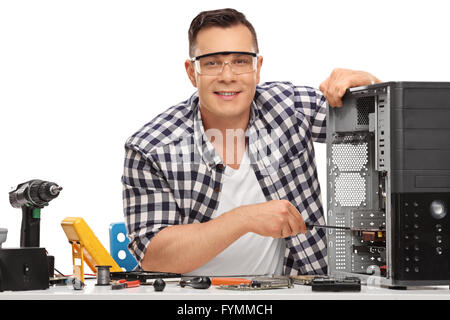 Young-PC-Techniker reparieren eines defekten Desktop-Computers und schaut in die Kamera, die isoliert auf weißem Hintergrund Stockfoto