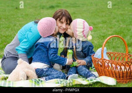 Zwei Töchter küssen Mutter unterwegs ein Picknick Stockfoto