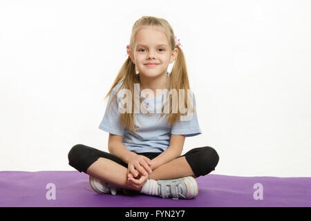 Sechs Jahre alten Mädchen Sportler sitzen auf einem Teppich Stockfoto