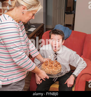 Ein Junge bläst seine Kerzen auf seinen 16. Geburtstagskuchen im Vereinigten Königreich Stockfoto