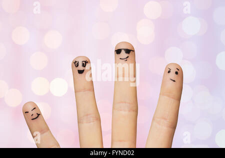 Nahaufnahme von vier Fingern mit Smiley-Gesichter Stockfoto